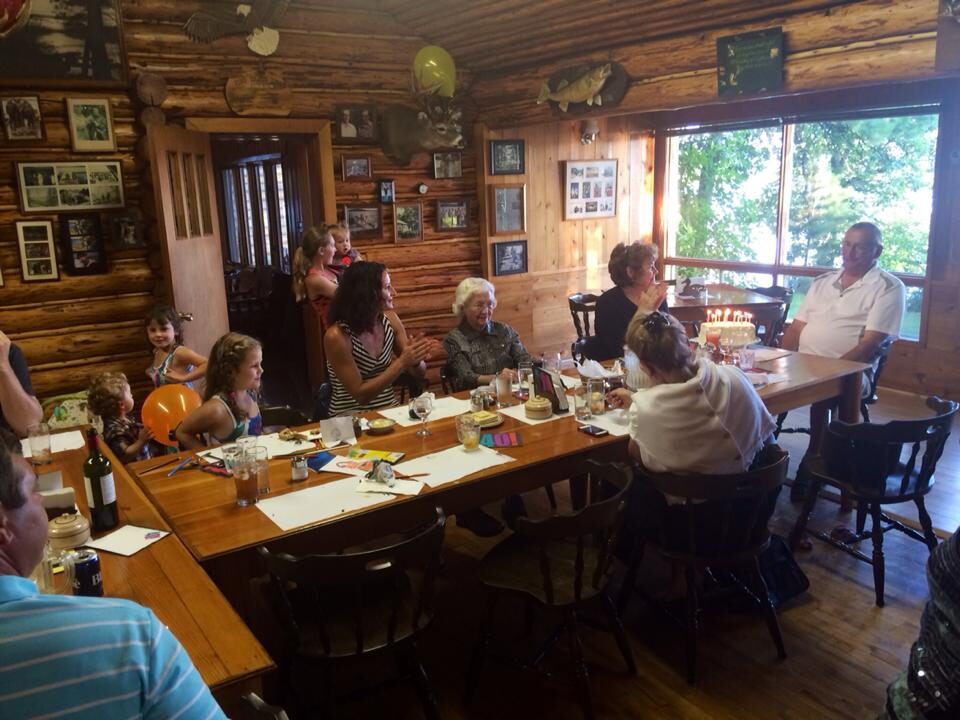 Family gathered around the long table in the log dining hall for a celebration